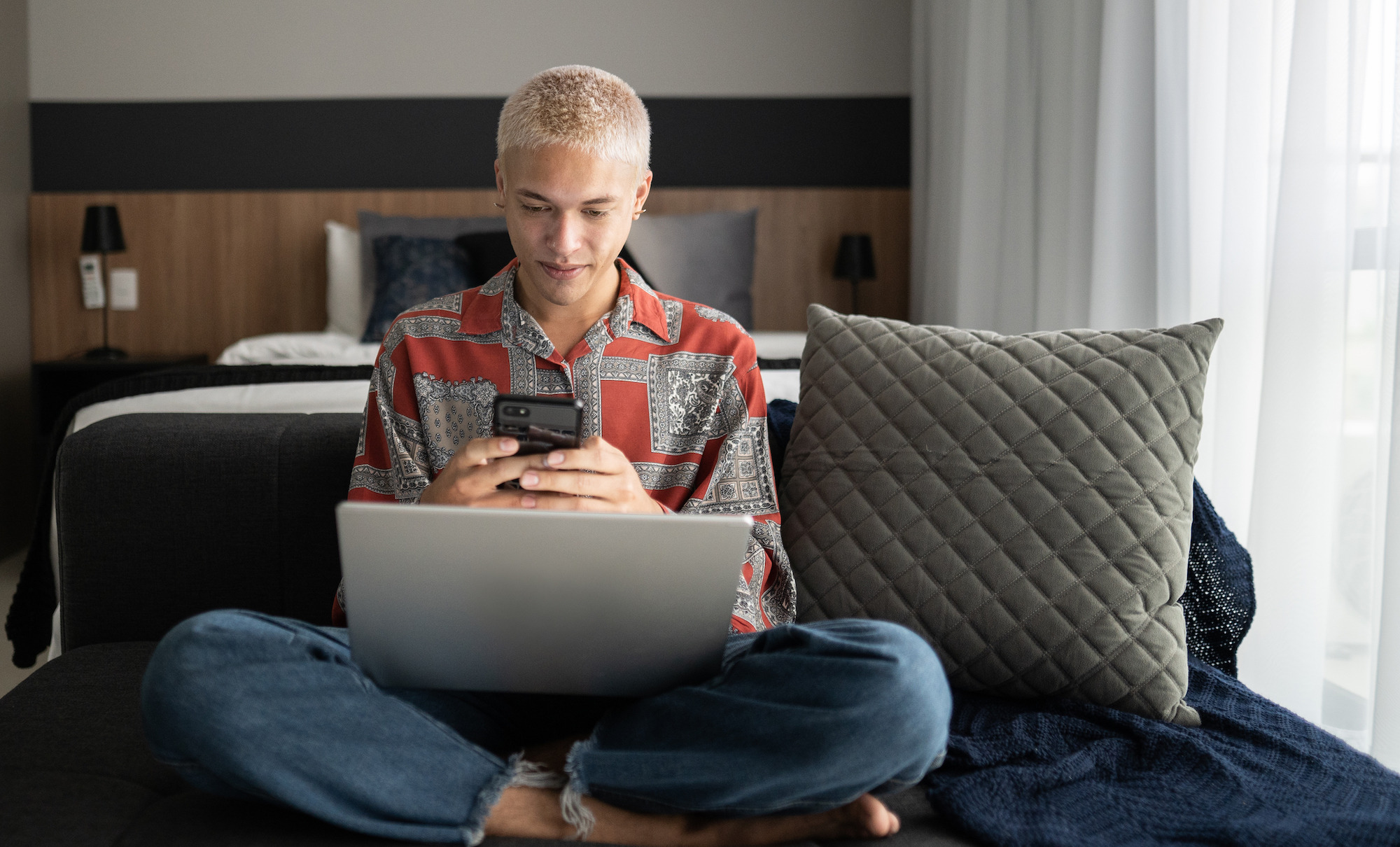 Gen Z young man using phone and laptop at home